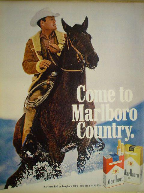 Roy Sickner on horseback in the snow, in a fleece-lined jacket and white cowboy hat, beside the tagline 'Come to Marlboro Country' — late-1960s Marlboro magazine campaign.